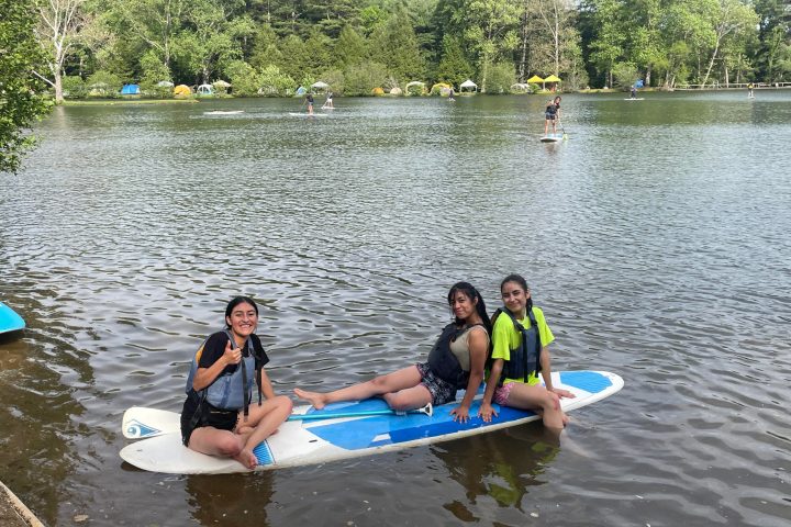 a group of people standing next to a body of water